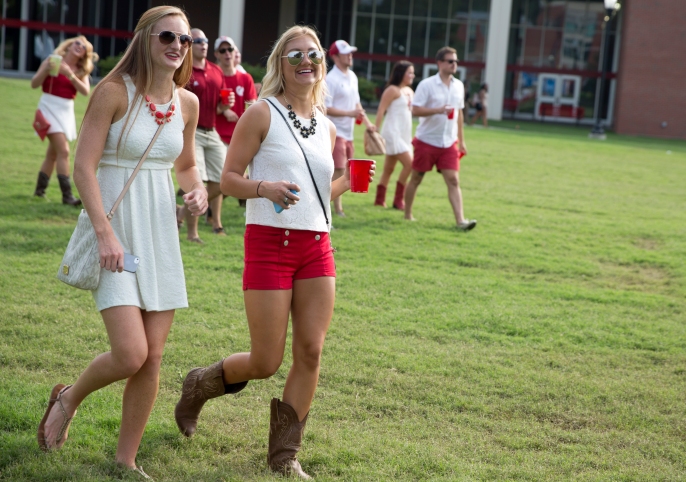 Western Kentucky University sophomore Brittany Harper (19) and junior AJ Ecton (20) walk across South Lawn, a popular tailgating area on campus, before WKU's first football game.